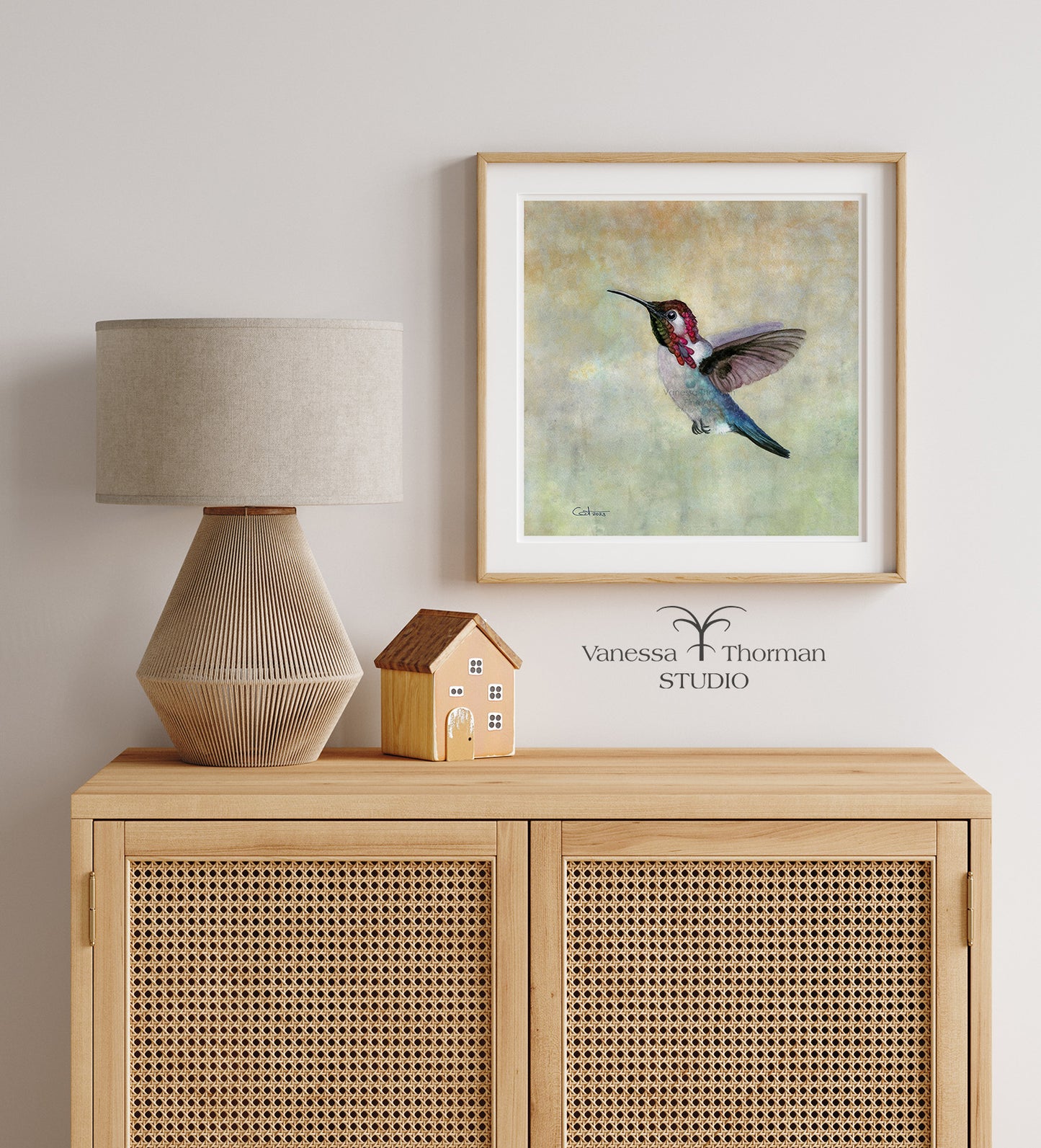 Framed Bee Hummingbird watercolor art print by Vanessa Thorman hanging over a wood hutch