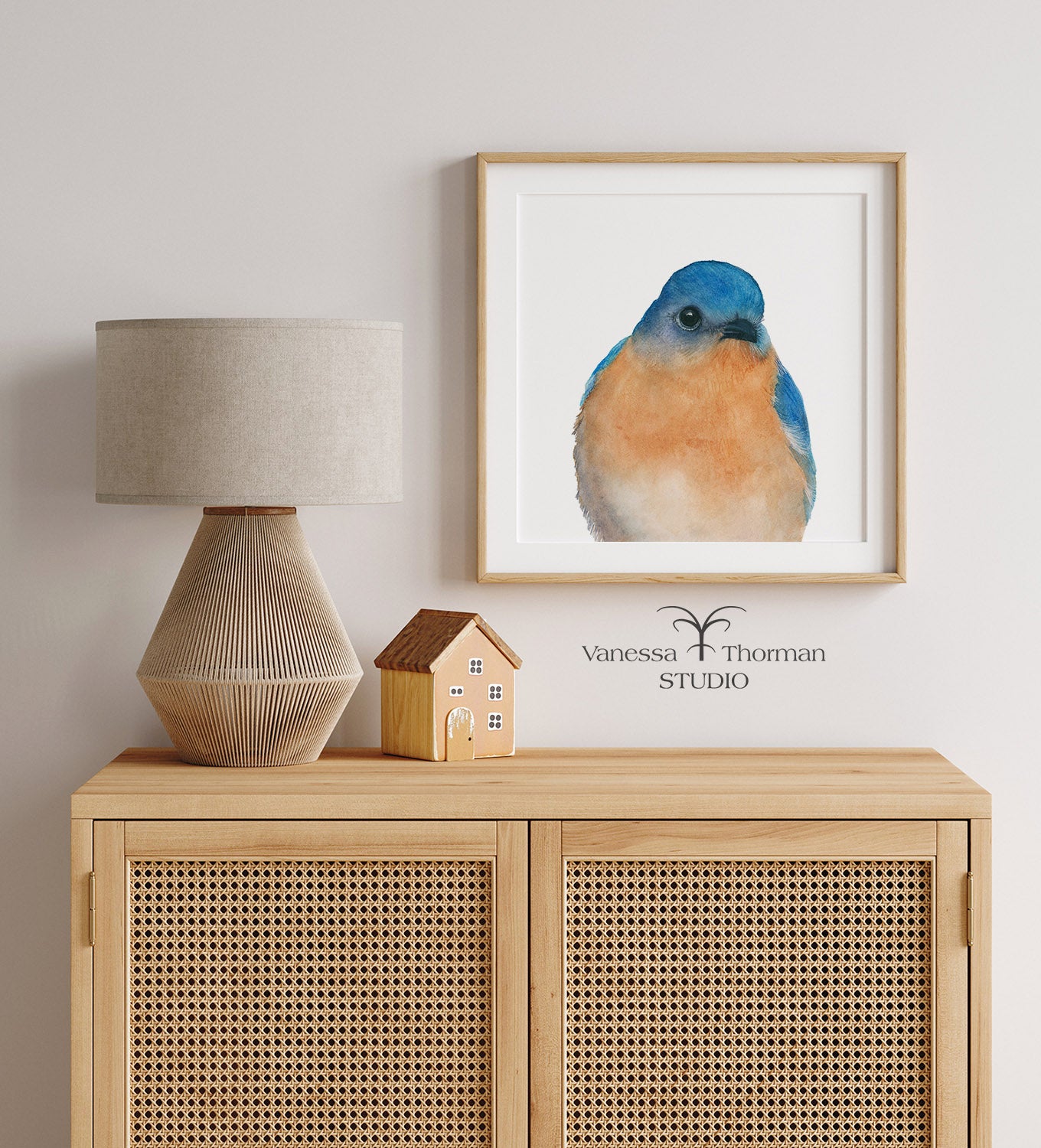 "Bernard," a close-up Eastern Bluebird watercolor art print by Vanessa Thorman, framed and hanging above a wood hutch