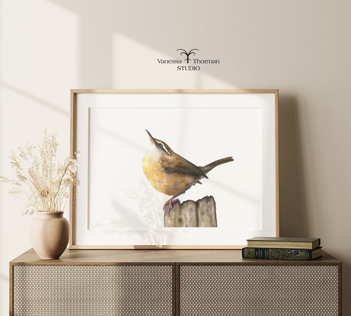 Framed Carolina Wren watercolor art print by Vanessa Thorman on a console table