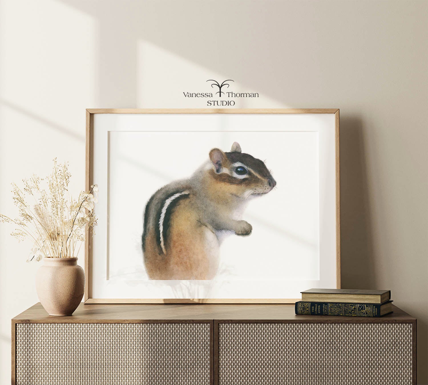 Framed Chipmunk Watercolor Art Print with a white background on a console table