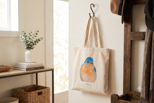 Eastern Bluebird watercolor art canvas tote hanging on a dark metal hook in a bright, modern entryway.