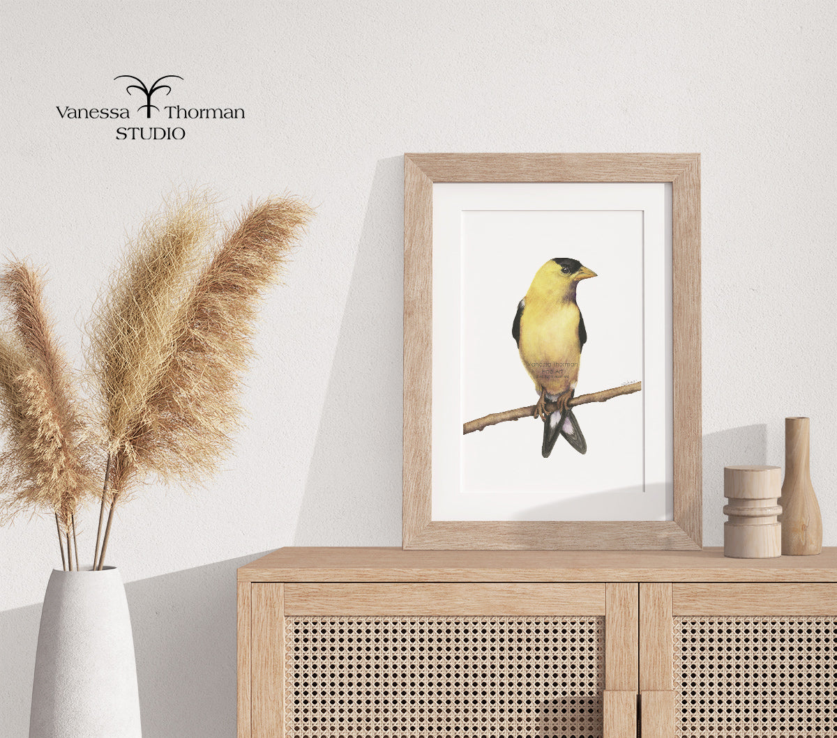 Framed Goldfinch Watercolor Art Print by Vanessa Thorman on a console table