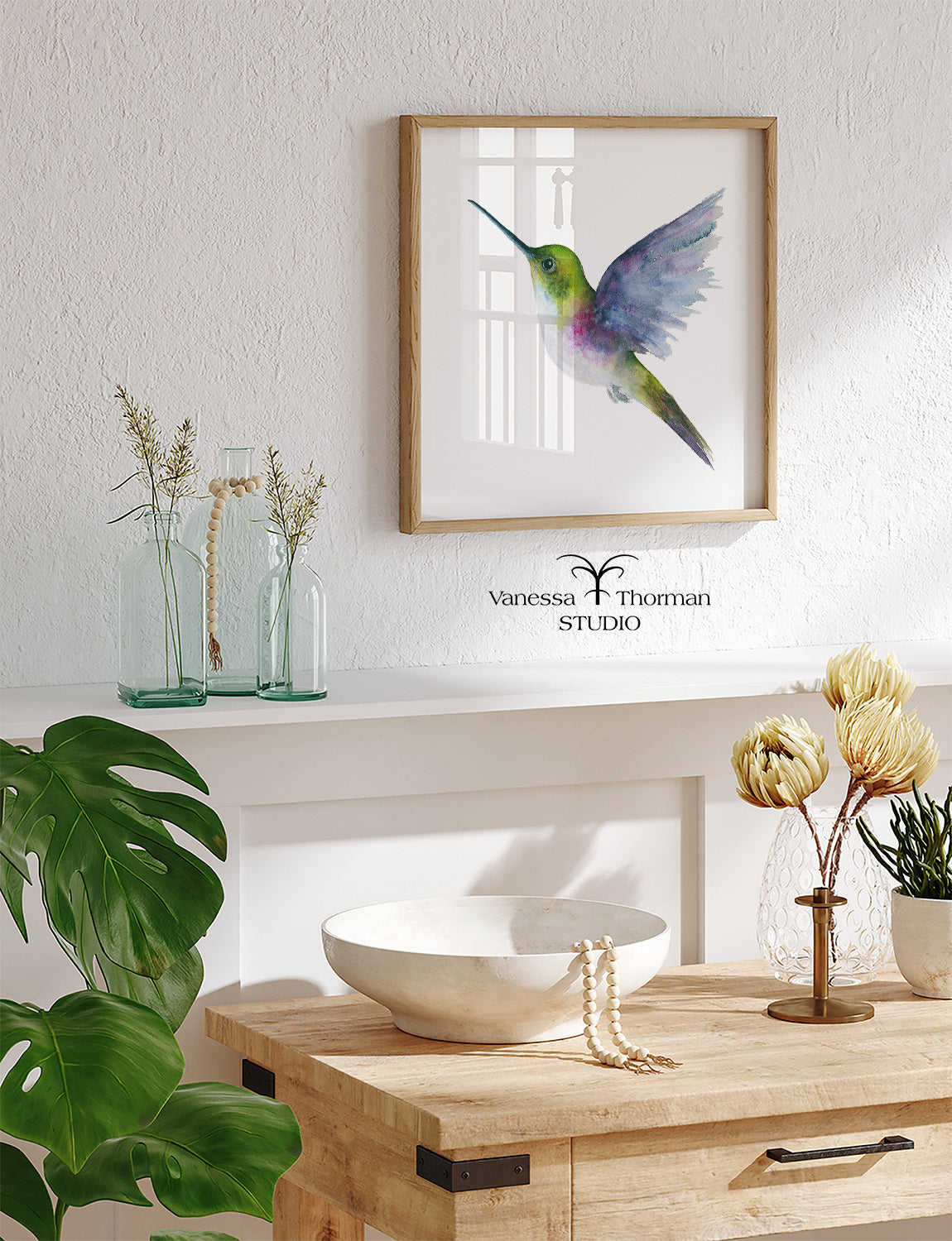 Framed Hummingbird in flight watercolor art print by Vanessa Thorman hanging in a home