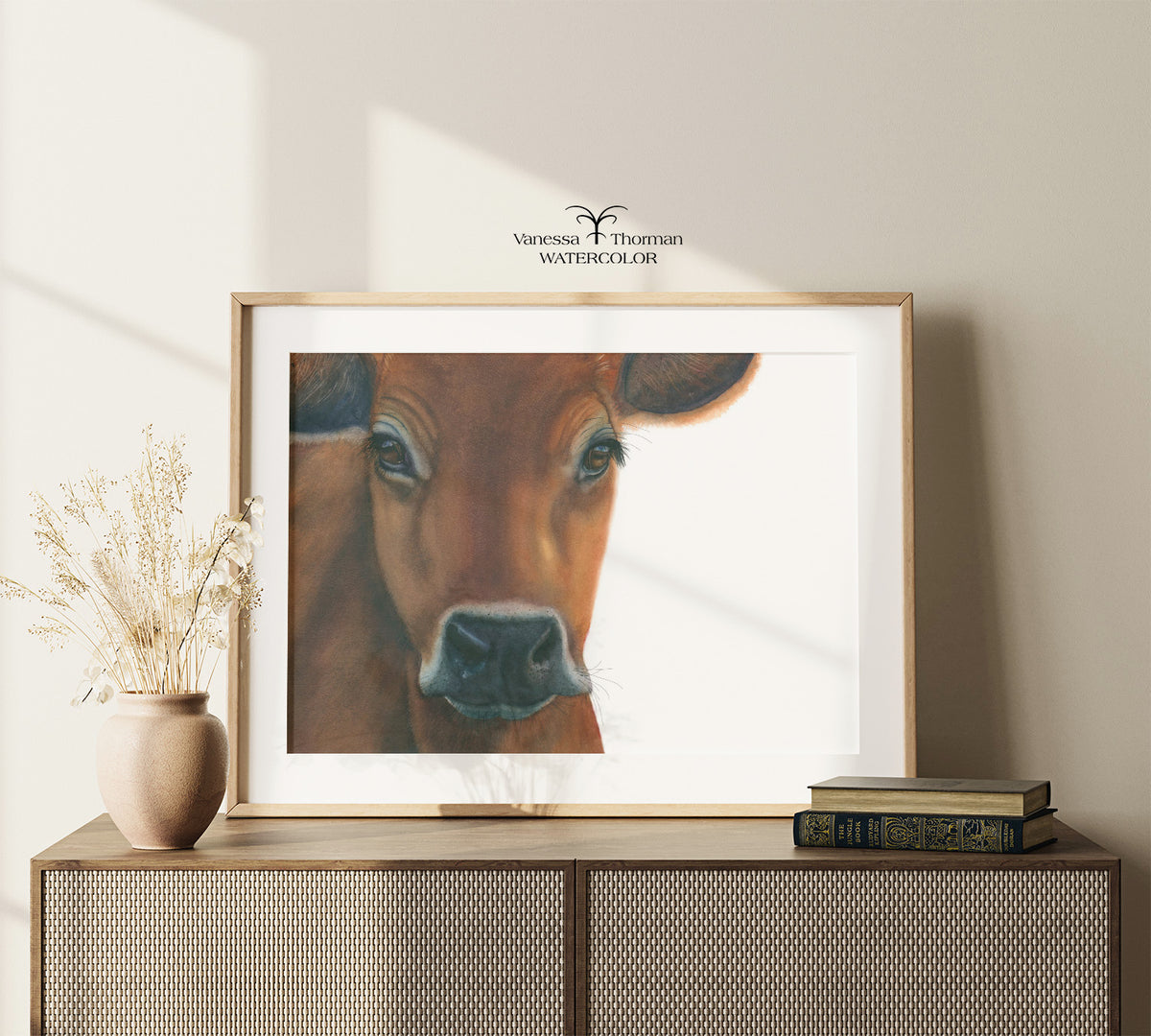 Framed "Owen" Jersey Cow watercolor art print by Vanessa Thorman on a console table