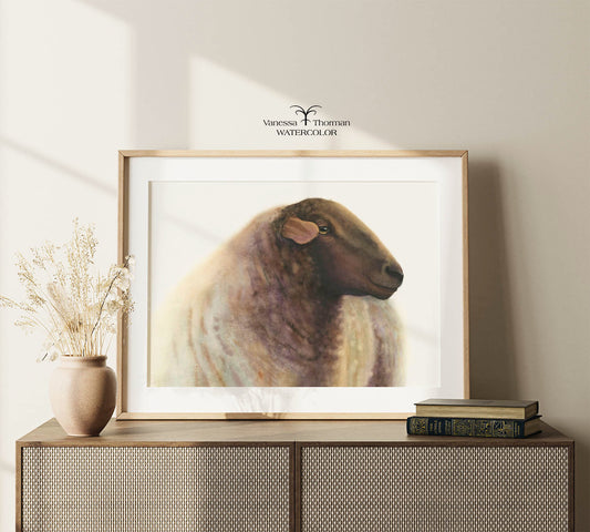 Framed "Theo" sheep watercolor art print by Vanessa Thorman displayed on a console table