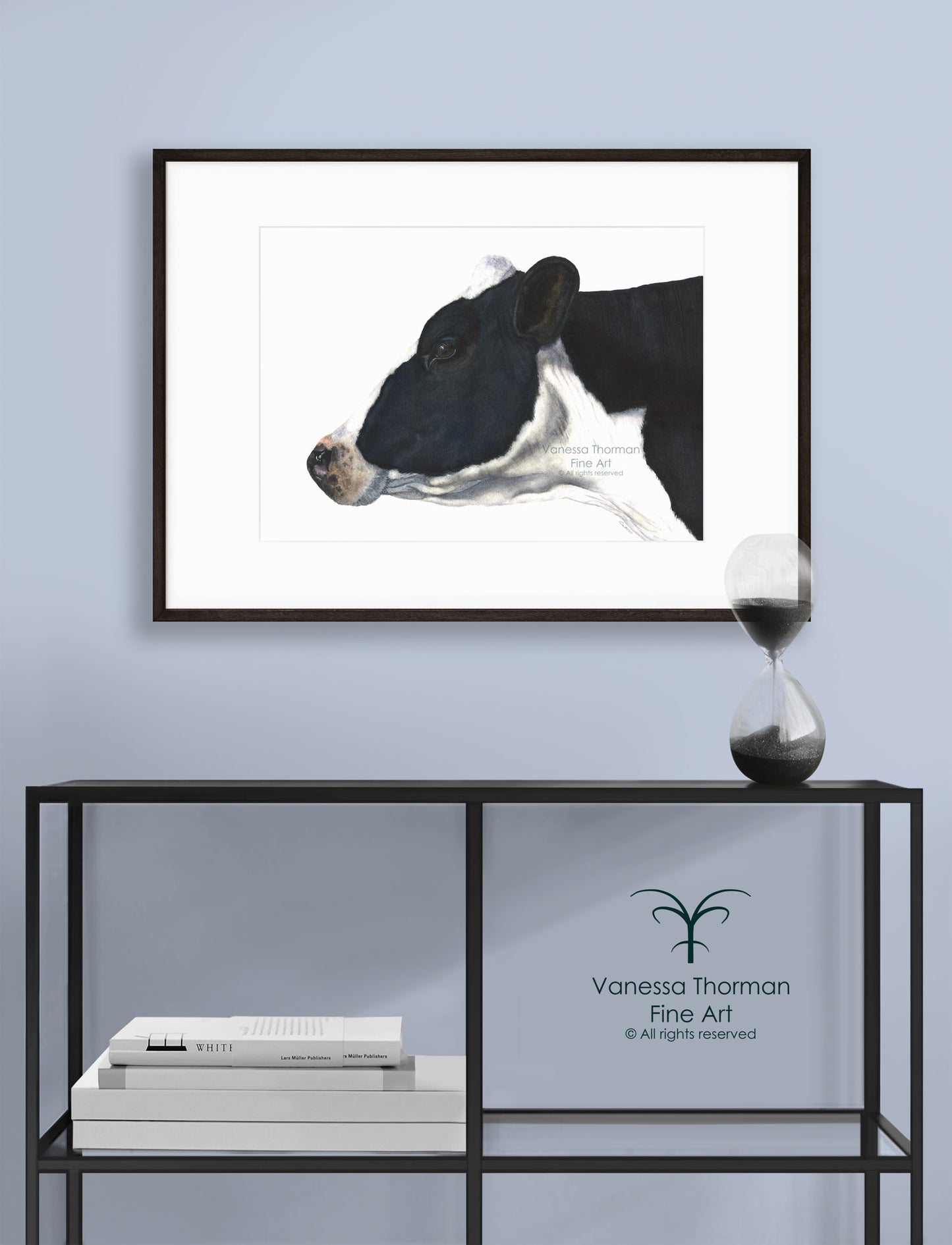 Framed "Belle of the Ball" Holstein Cow watercolor art print by Vanessa Thorman displayed on a console table