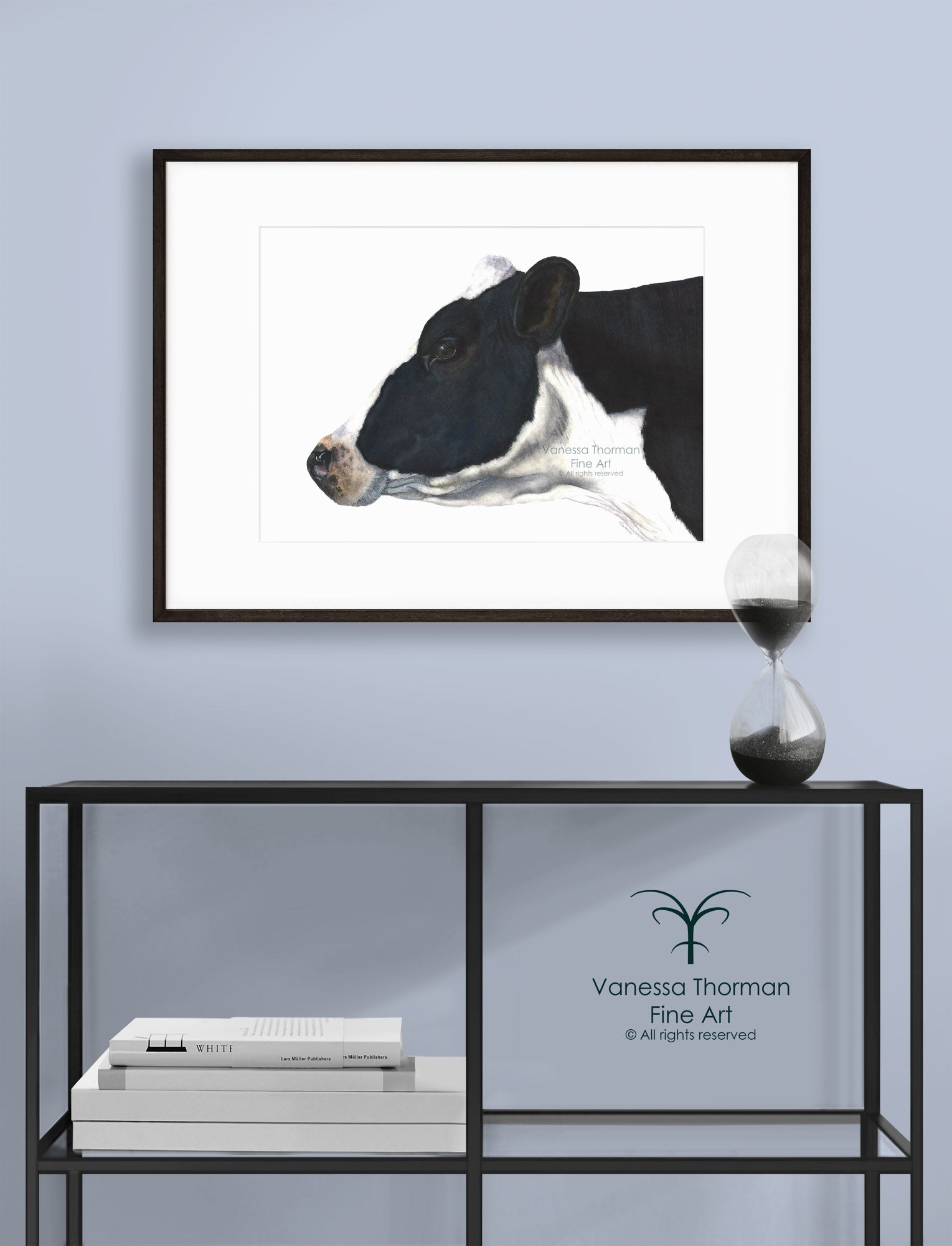 Framed "Belle of the Ball" Holstein Cow watercolor art print by Vanessa Thorman displayed on a console table