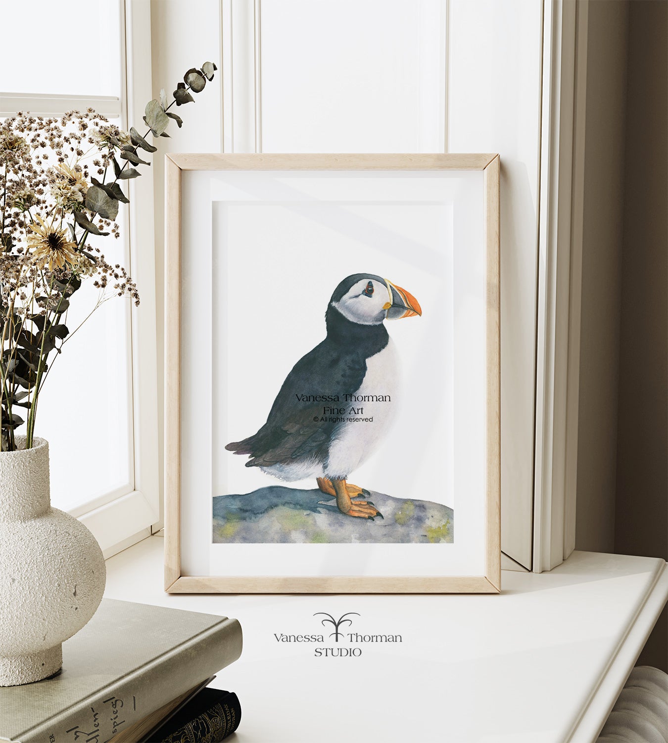 Framed  puffin watercolor art print on a plain background on a windowsill