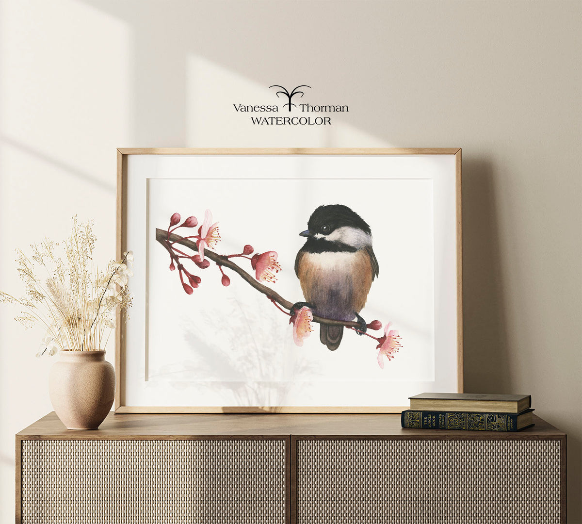 Framed "Spring Chickadee" watercolor art print by Vanessa Thorman on a console table