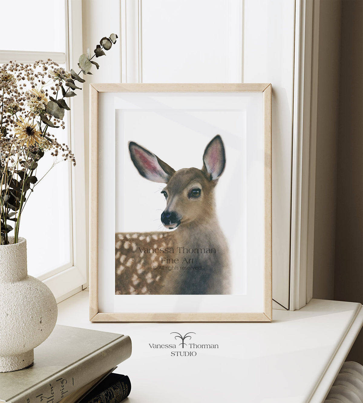 Framed White-Tailed Fawn watercolor art print by Vanessa Thorman displayed on a windowsill