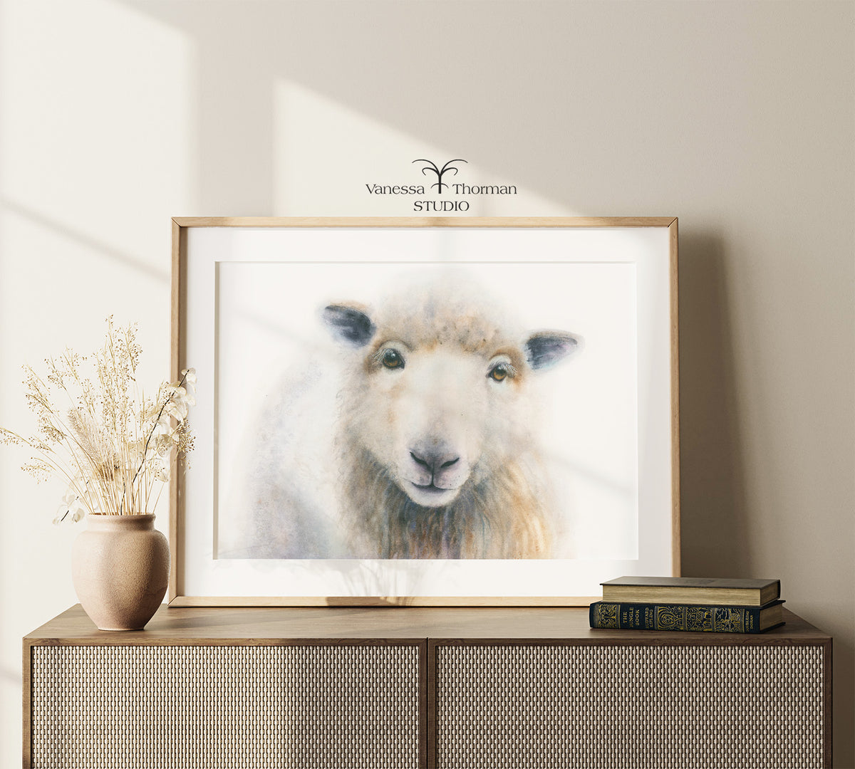 Framed "William" sheep watercolor art print by Vanessa Thorman displayed on a console table